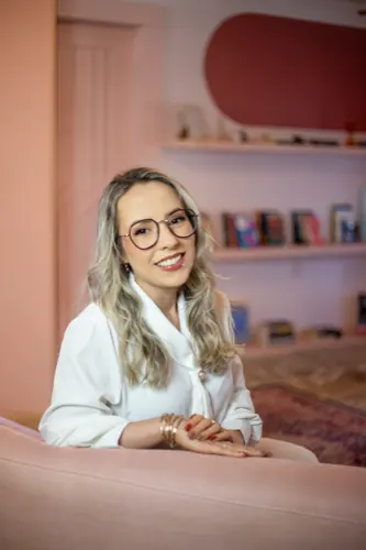 Daniela Bézi sorrindo em frente a uma estante de livros