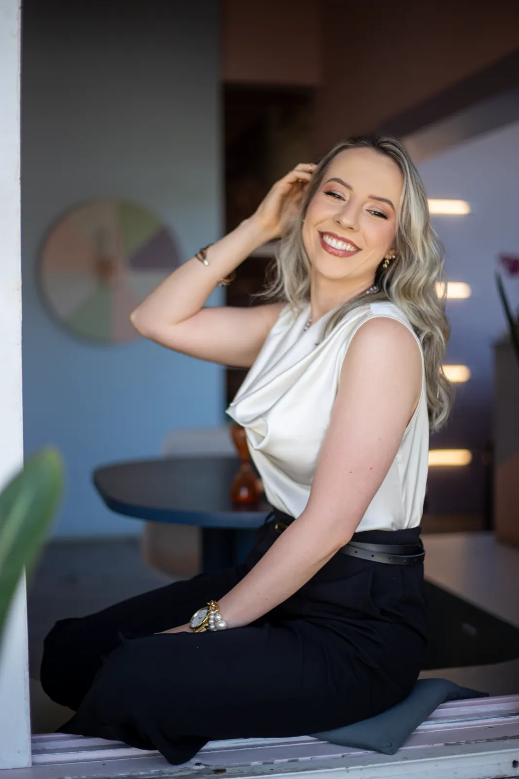 Daniela Bézi sorrindo, sentada junto à janela