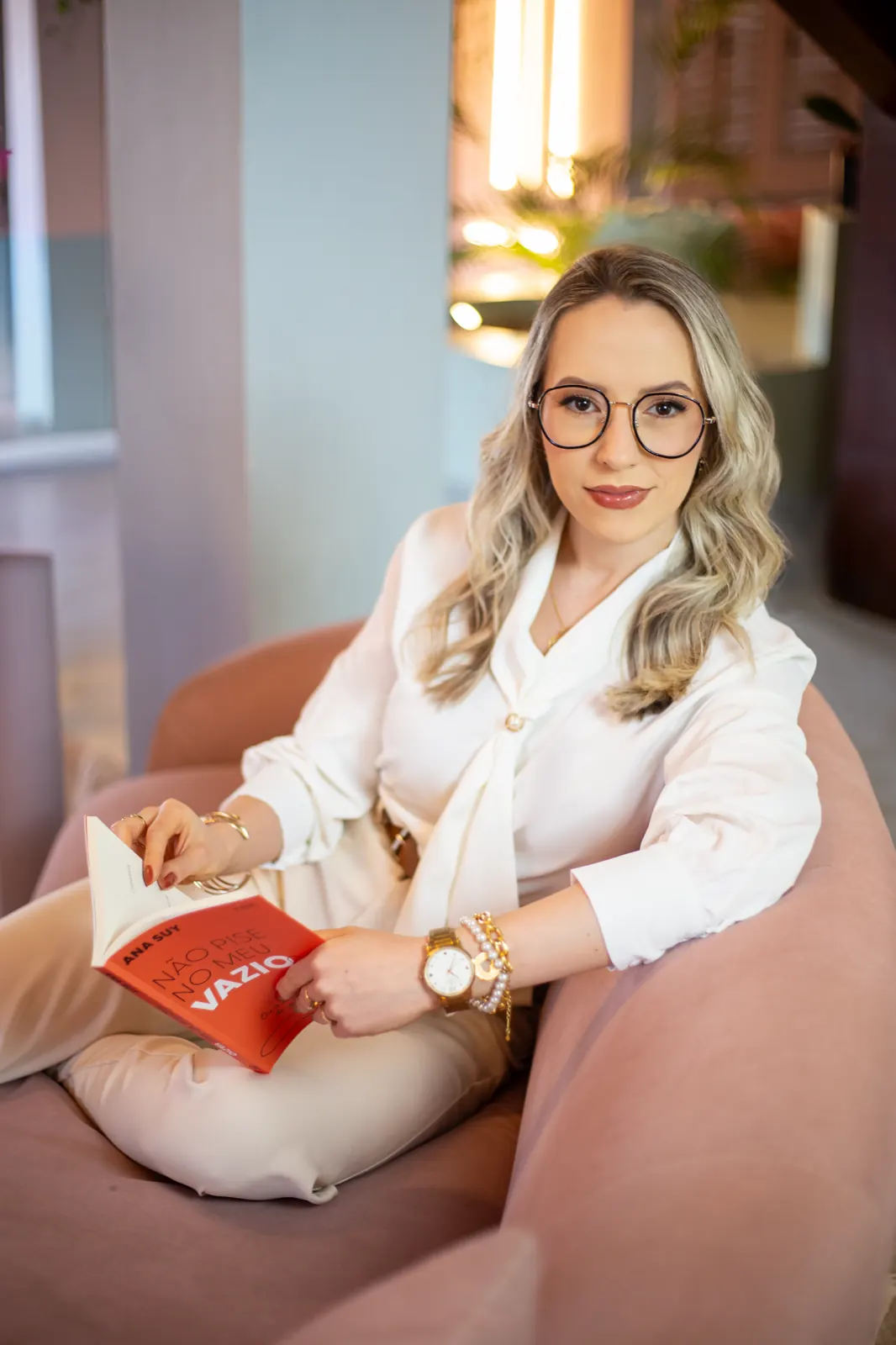 Daniela Bézi sentada em um sofá, segurando um livro